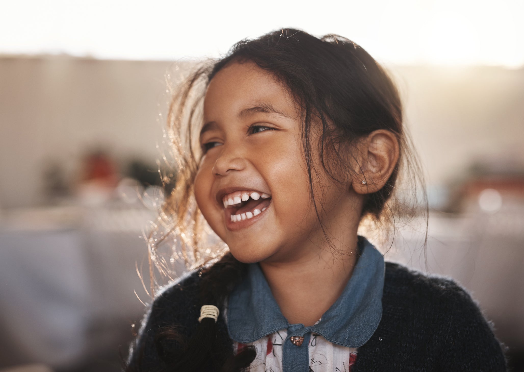 A little girl with brown hair smiling.
