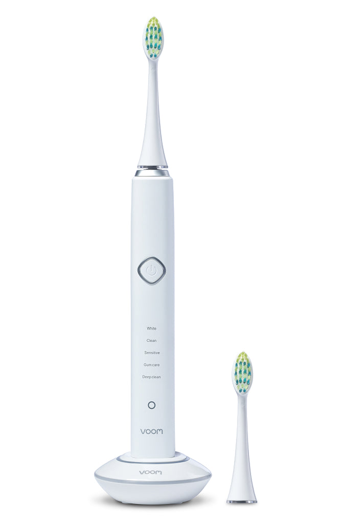 White electric toothbrush with a charging base on a white background