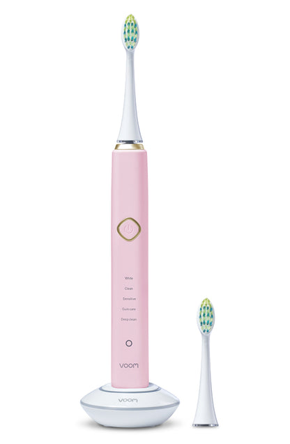 Pink electric toothbrush with a white base on a white background